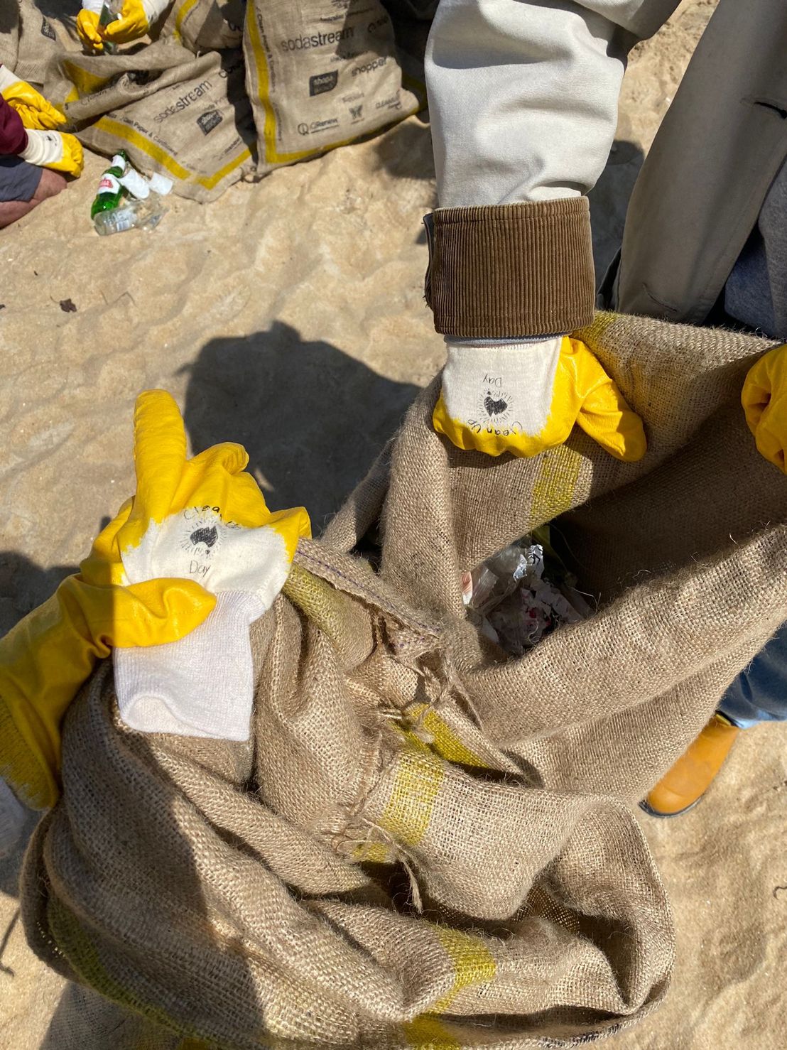 Claire Beach Clean Up with MESSA - TOMRA Cleanaway Connecting communities through local clean up events, this image shows hands holding plastic rubbish during a beach clean up for Clean Up Australia day.