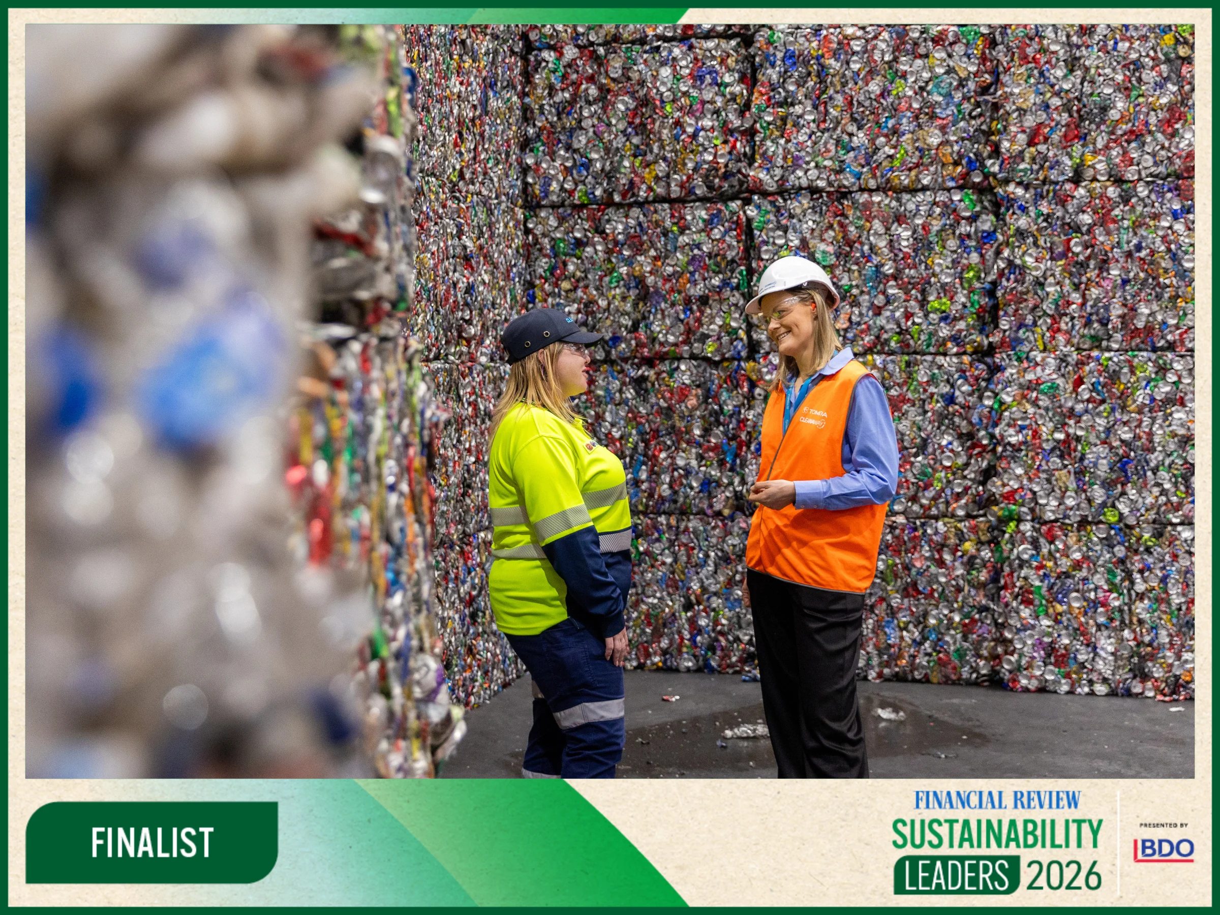 AFR Sustainability Leaders Finalists 2026 website banner 1 - TOMRA Cleanaway Two workers in neon safety vests and hard hats stand and chat in front of a wall of compressed plastic bottle caps in a TOMRA Cleanaway recycling facility, with an AFR logo boarder around image.