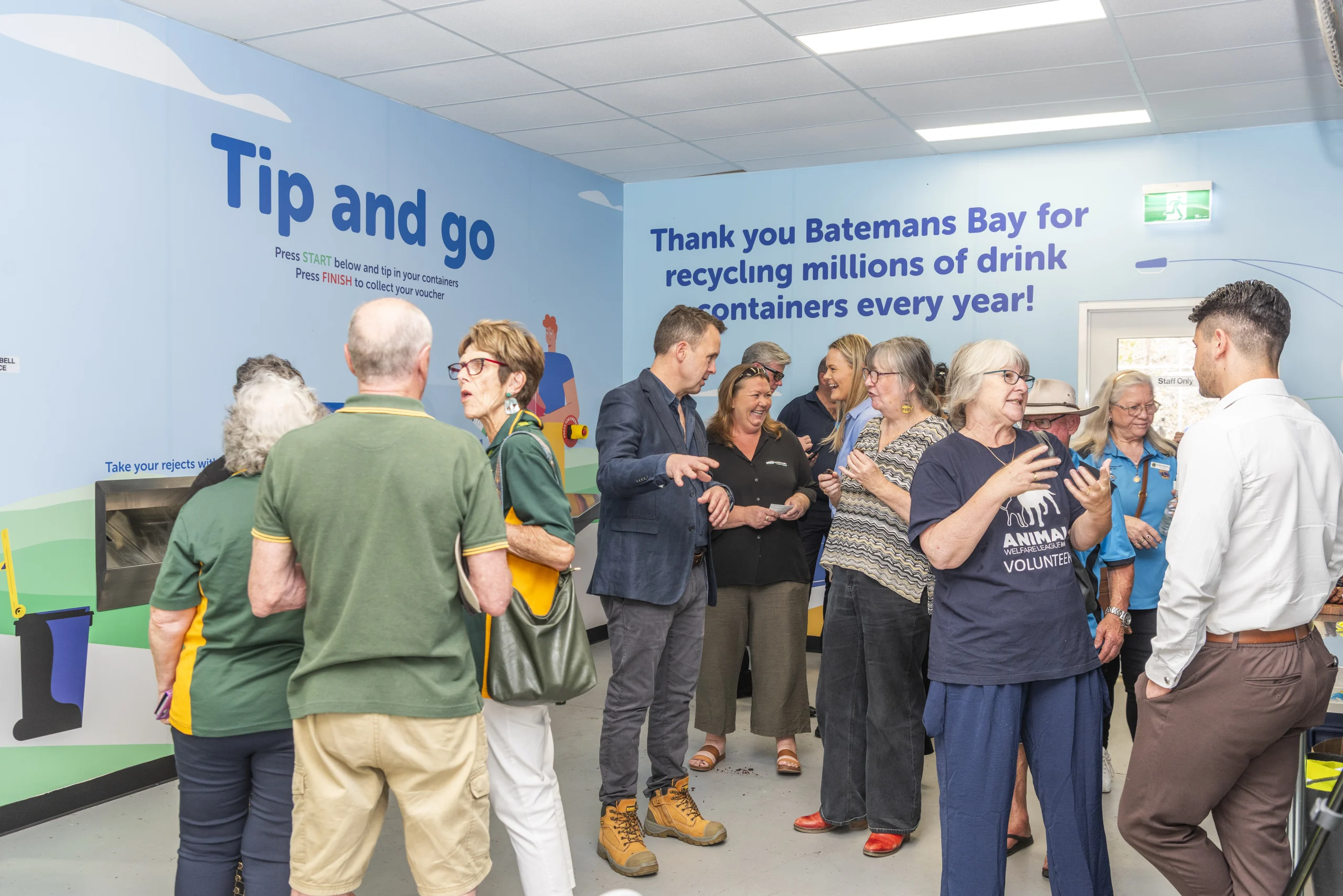 Group of people wearing different uniforms gathered in Return and Earn depot